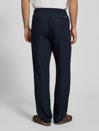 Männermodel trägt Wide Fit Leinenhose mit Viskose-Anteil Modell 'Malvin' von Blend in Dunkelblau, elastischer Bund, Gesäßtasche, Ganzkörperansicht Rückansicht.