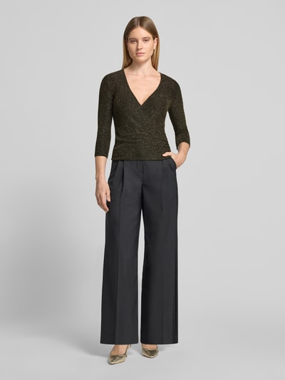 Kobiecy model nosi szimmerndes Blusenshirt mit V-Ausschnitt von Christian Berg Woman Selection, materiał z dodatkiem stretchu, krój slim fit, czarny połysk, długość tyłu w rozmiarze S: 55 cm, długość rękawa w rozmiarze S: 47 cm, widok całej sylwetki z przodu.