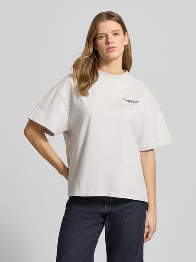 Kobieta nosi damski t-shirt z bawełny, krój oversized, model 'MARIALVA' Pegador z wyhaftowanym logo, okrągły dekolt, długość tyłu 61 cm w rozmiarze S, widok całej sylwetki z przodu.