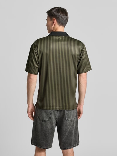 Męskimodel nosi koszulkę polo Regular Fit Poloshirt mit Label-Print model 'Lama' od Wood Wood, zielone paski, krój regular fit, nadruk z logo, kołnierzyk polo, krótki zamek błyskawiczny, długość tyłu w rozmiarze M: 72 cm, ganzkörperansicht rückansicht.