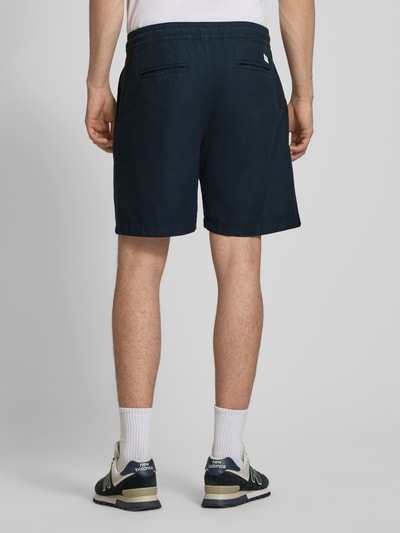 Męski model nosi Relaxed Fit Chinoshorts aus Baumwoll-Leinen-Mix od Pepe Jeans, granatowy kolor, jednolity, luźny krój, elastyczny pas z troczkiem, kieszenie boczne i pasplowane, bawełniano-lniana faktura, widok całej sylwetki od tyłu.