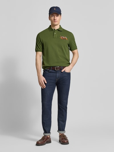 Męski model nosi Regular Fit Poloshirt aus reiner Baumwolle von Polo Ralph Lauren, efekt: jednolity kolor, krój regular fit, wyhaftowany motyw, kołnierzyk polo, dekolt w serek, krótkie zapięcie na guziki, krótkie rękawy z prążkowanym zakończeniem, dół z bocznymi rozcięciami, asymetryczny, wykończenie: pika, materiał: czysta bawełna, ujęcie: całe ciało z przodu.