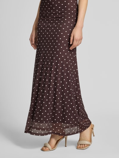 Frauenmodel trägt Maxirock im Allover-Look Modell 'Mimi Flute' von Forever New aus braunem Mesh mit weißen Punkten, A-Linie, Nahaufnahme Unterkörper. Bundweite bei Größe 36: 43 cm, Gesamtlänge bei Größe 36: 100 cm.