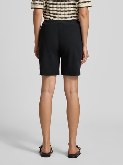 Frauenmodel trägt schwarze Shorts mit elastischem Bund Modell 'Cissie' von Soyaconcept aus reiner Baumwolle, Ganzkörperansicht Rückansicht.