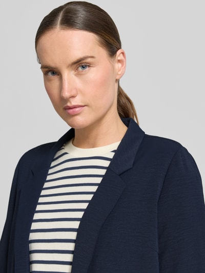 Modelka kobieca ma na sobie Regular Fit Blazer mit Reverskragen und Paspeltaschen od Zero, kolor granatowy, struktura gładka, kontekst: damska marynarka Zero, krój regular fit, otwarty krój, kołnierz z klapami, kieszenie z lamówką, długość tyłu w rozmiarze 36: 65 cm, szerokość w rozmiarze 36: 39 cm, długość rękawa w rozmiarze 36: 60 cm, zbliżenie na górną część ciała.