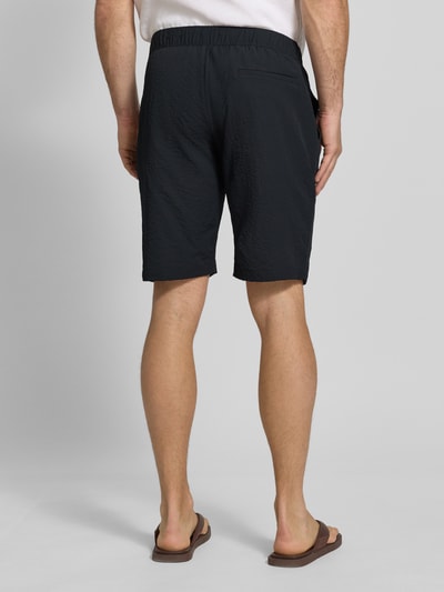 Männermodel trägt Shorts mit elastischem Bund und Eingrifftaschen von MCNEAL, Regular Fit, Strukturmuster, Rückansicht Ganzkörperansicht.