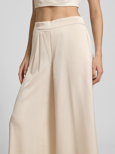 Kobieta ma na sobie Stoffhose mit elastischem Bund od V by Vera Mont, satynowy materiał, krój relaxed fit, szeroka nogawka, kremowy kolor, detal pasa, Szerokość w rozmiarze 36: 28 cm, długość wewnętrzna nogawki 79 cm, zbliżenie na górną część ciała
