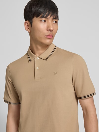 Männermodel trägt Regular Fit Poloshirt mit Logo-Stitching von bugatti in Beige, Reine Baumwolle, Polokragen, kurze Knopfleiste, Label-Detail, Nahaufnahme Oberkörper.