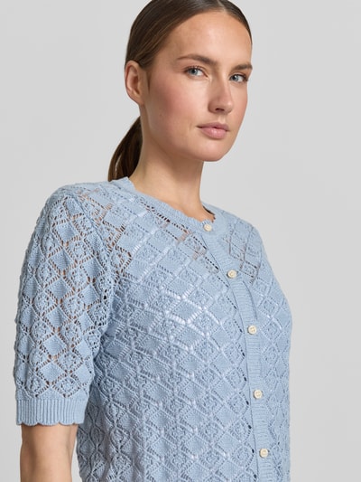 Modelka kobieca ma na sobie Regular Fit Strickjacke aus reiner Baumwolle Modell 'SOFIA' od Selected Femme, jasnoniebieski ajur, guziki, okrągły dekolt, krótki rękaw, półzbliżenie górnej części ciała.