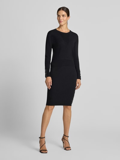 Vrouwenmodel draagt gebreide pullover uit Viscosemix Model 'MAGLIA' van Liu Jo, smalle pasvorm, ribboorden, ruglengte maat S 54 cm, mouwlengte S 61 cm, zwart, ribtextuur, volledige lichaamsaanzicht voorkant.