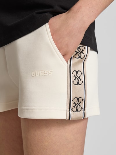 Frauenmodel trägt Shorts mit Kordelzug und Logo-Print Modell 'BRITNEY' von Guess, Baumwoll-Mix, cremefarben, Nahaufnahme Oberschenkel.