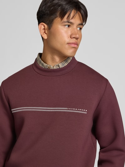 Mężczyznamodel nosi Relaxed Fit Sweatshirt mit Viskose-Anteil Modell 'Fusion' von JACK & JONES, Mieszanka materiałów z dodatkiem wiskozy, nadruk z logo, krój z długim rękawem, wykończenia: elastyczne, długość tyłu w rozmiarze M: 66 cm, długość rękawów: 66 cm, ujęcie: zbliżenie górnej części ciała.