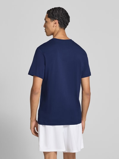 Männermodel trägt Regular Fit T-Shirt aus reiner Baumwolle von Nike in Dunkelblau und weiße Shorts, Ganzkörperansicht Rückansicht. Herren T-Shirt von Nike.