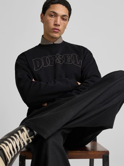Männermodel trägt Sweatshirt mit Label-Stitching von Diesel in Schwarz, Reine Baumwolle, Lockerer-Schnitt, Gerippte-Abschlüsse, Rundhalsausschnitt, Rückenlänge bei Größe M 67 cm, Nahaufnahme Oberkörper.