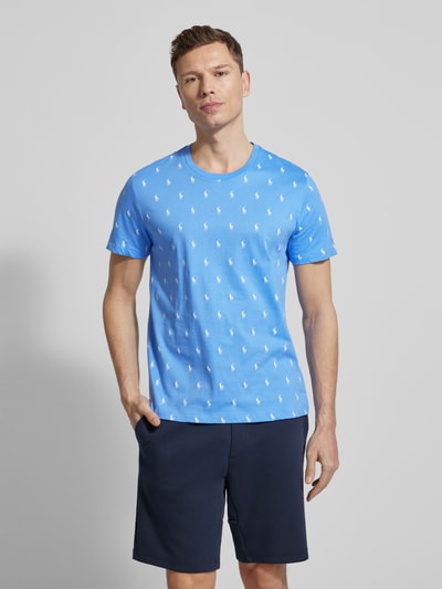 Männermodel trägt Regular Fit Pyjama-Oberteil aus reiner Baumwolle Modell 'CREW-SLEEP-TOP' von Polo Ralph Lauren Underwear, blau mit weißem Polo-Pony-Muster, Crew-Neck und kurzen Ärmeln, Ganzkörperansicht von vorne.