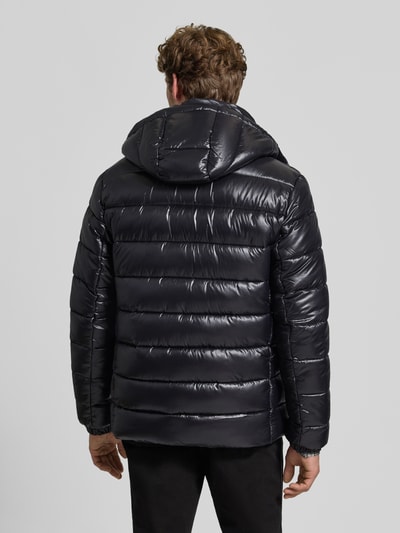 Männermodel trägt schwarze Steppjacke mit abnehmbarer Kapuze Modell 'FLORIAN' von Save The Duck, glatte Struktur, Ganzkörperansicht Rückansicht.
