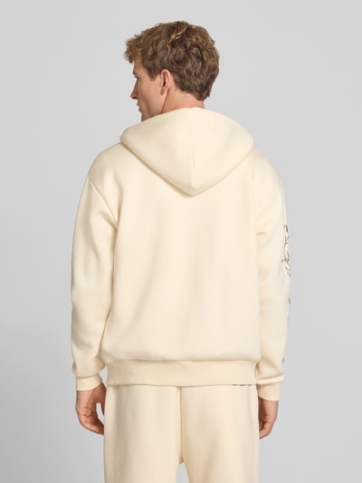 Männermodel trägt Relaxed Fit Sweatjacke mit Kapuze von REVIEW in Creme, Baumwoll-Mix, florale Stickerei, Ganzkörperansicht Rückansicht.