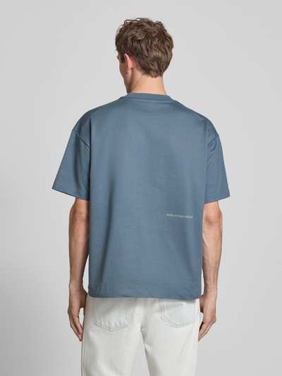 Männermodel trägt Boxy Fit T-Shirt aus reiner Baumwolle von Marc O'Polo Denim, unifarben, Label Print, Ganzkörperansicht Rückansicht.