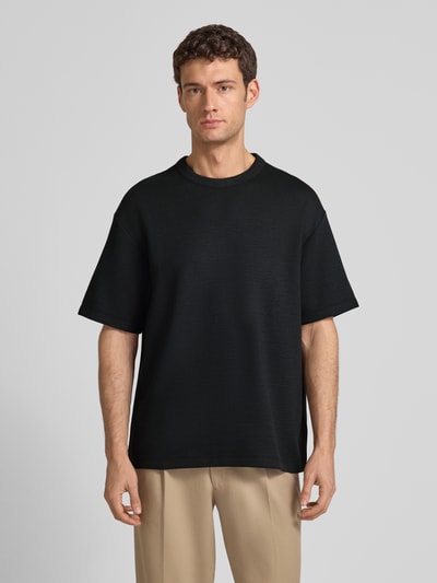Männermodel trägt T-Shirt mit Rundhalsausschnitt Modell 'CRINKLE CREPE SPACER' von CK Calvin Klein, schwarz, Strukturmuster, Ganzkörperansicht von vorne. Material-Mix mit Modal-Anteil, Relaxed Fit, Rückenlänge bei Größe M 71 cm.