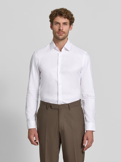 Männermodel trägt weißes Super Slim Fit Businesshemd aus reiner Baumwolle von Jake*s, kombiniert mit brauner Hose, Ganzkörperansicht von vorne.