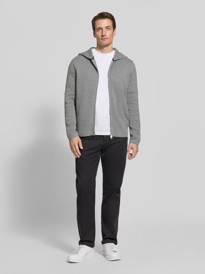 Männermodel trägt Regular Fit Pullover aus reiner Baumwolle von Marc O'Polo in Hellgrau, kombiniert mit dunkler Hose, Ganzkörperansicht von vorne. Herren Pullover von Marc O'Polo.