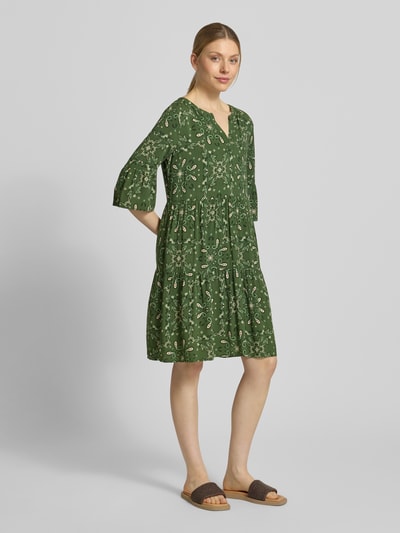 Kobiece model prezentuje Relaxed Fit Minikleid aus reiner Viskose od Christian Berg Woman Selection, zielony paisley, długość mini, tunikowy dekolt, rękaw 3/4, czysta wiskoza, długość pleców w rozmiarze 36: 89 cm, szerokość w rozmiarze 36: 49 cm, długość rękawa w rozmiarze 36: 39 cm, widok całej sylwetki z przodu.