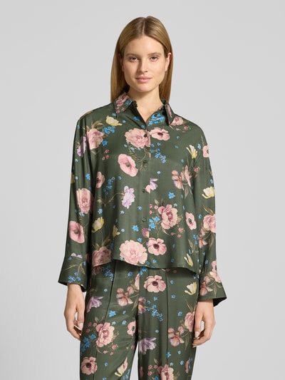 Vrouwenmodel draagt Regular Fit Bluse aus Viskose im Allover-Look van Oui, zuiver viscose, all-over look, overhemdkraag, knoopsluiting, ruglengte maat 36: 61 cm, mouwlengte maat 36: 55 cm, bloemenprint op donkergroene achtergrond. Ganzkörperansicht van voren.