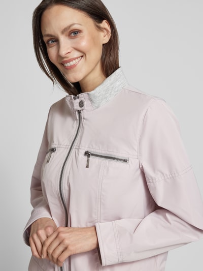Kobiece model prezentuje Jacke mit Zweiwege-Reißverschluss od Amber & June, jasnoróżowy kolor, krój regular fit, stójka, kieszenie na suwak i na guziki, szerokość w rozmiarze 36: 51 cm, długość tyłu 56 cm, długość rękawa 60 cm, szerokość ramion 42 cm, zbliżenie na górną część ciała z przodu