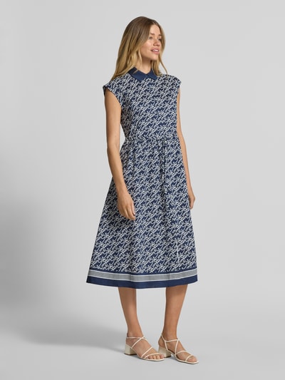 Frauenmodel trägt Hemdblusenkleid in Midi-Länge aus Baumwolle-Seide-Mix von Tommy Hilfiger mit Allover-Muster, tailliert, ärmellos, Knopfleiste, Taillenband, Logo-Print, in Blau-Weiß, Ganzkörperansicht von vorne.