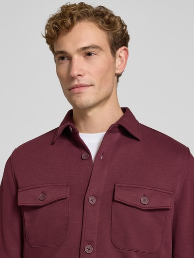 Männermodel trägt Overshirt mit Knopfleiste von MCNEAL in Bordeaux, Brusttaschen, Material-Mix, Nahaufnahme Oberkörper.