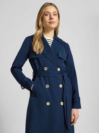 Vrouwenmodel draagt Zweireihiger Trenchcoat mit Bindegürtel van MICHAEL Michael Kors in regular fit, marineblauw, met dubbele rij knopen, reverskraag en strikceintuur, ruglengte maat S 47 cm, schouderbreedte 40 cm, borstwijdte 50 cm, mouwlengte 63 cm, detailopname bovenlichaam.