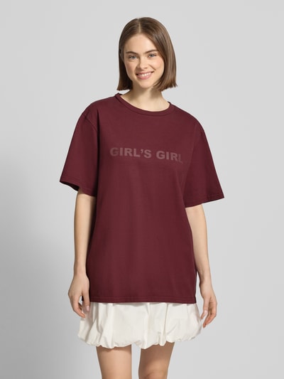 Frauenmodel trägt Oversized T-Shirt mit Statement-Print von OH APRIL in Dunkelrot, Reine Baumwolle, Oversized-Fit, Gerippter Rundhalsausschnitt, Rückenlänge bei Größe S 70 cm, Ganzkörperansicht von vorne.
