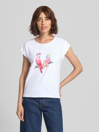 Frauenmodel trägt T-Shirt mit Motiv-Print und Pailletten von MORE & MORE im Baumwoll-Elasthan-Mix, weiß, Ganzkörperansicht von vorne.