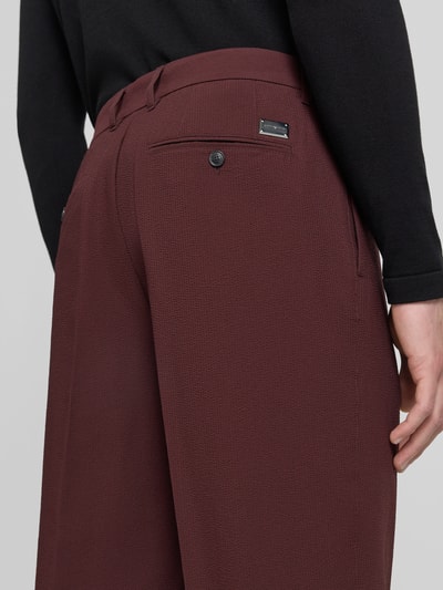 Männermodel trägt Anzughose mit Eingrifftaschen von Emporio Armani in Bordeaux, fein strukturiert, Material-Mix mit Stretch-Anteil, Detailaufnahme Rückansicht. Bundweite bei Größe 50: 45 cm, Innenbeinlänge: 85 cm, Regular-Fit.