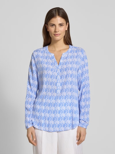 Frauenmodel trägt Regular Fit Schlupfbluse aus reiner Viskose von Christian Berg Woman mit floraler Allover-Print, Tunika-Kragen, langärmelig, überwiegend in Blau und Weiß, Oberflächenstruktur glatt, Ganzkörperansicht von vorne.