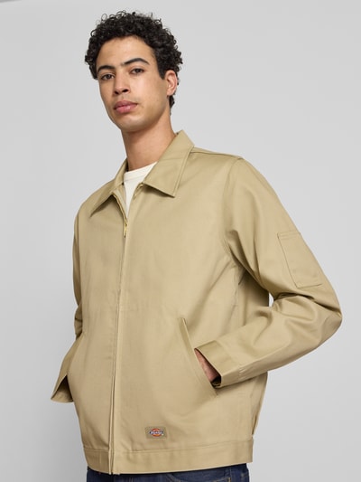 Männermodel trägt Jacke mit Reißverschluss Modell 'UNLINED EISENHOWER' von Dickies in Beige, Material-Mix, Regular-Fit, Eingrifftaschen, Label-Detail, Ganzkörperansicht von vorne.