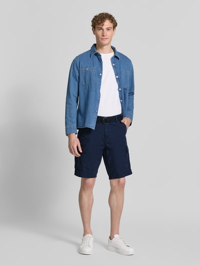 Männermodel trägt Regular Fit Bermudas mit Cargo-Taschen von Petrol aus reiner Baumwolle, dunkelblau, Ganzkörperansicht von vorne. Bundweite bei Größe M: 45 cm, Innenbeinlänge bei Größe M: 27 cm, Gesäßtaschen.