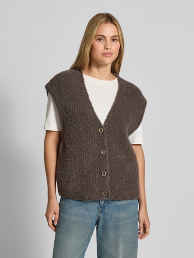 Kobiece model nosi kamizelkę Relaxed Fit Weste mit Alpaka-Anteil Model 'Zolly' od American Vintage, mieszanka bawełny i wełny z alpaki, imitacja dzianiny, listwa guzikowa, dekolt w serek, długość tyłu w rozmiarze XS/S: 57 cm, widok całej sylwetki z przodu.