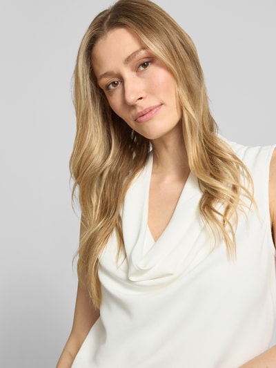 Vrouwenmodel draagt Top mit Wasserfall-Ausschnitt van comma, crèmekleurige viscose-elastanmix, regular fit, detailopname bovenlichaam.