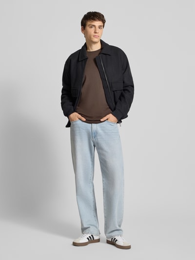 Męski model nosi Regular Fit T-Shirt aus reiner Baumwolle von Tommy Jeans, jednolity, z nadrukiem label, okrągły dekolt, krótki rękaw, dżersej, bawełna, widok całej sylwetki z przodu.