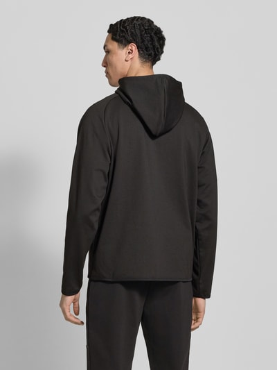 Männermodel trägt Regular Fit Sweatjacke mit Kapuze Modell 'Base' von Jack & Jones in Schwarz, elastischer Material-Mix, Rückenansicht Ganzkörperansicht.