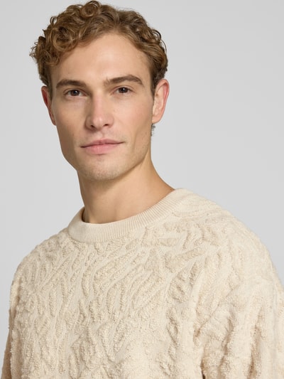 Męski model nosi Regular Fit Pullover mit Woll-Anteil Modell 'sweatio' od Matinique, mieszanka bawełny z dodatkiem wełny, imitacja dzianiny w fakturowany wzór, okrągły dekolt, beżowy kolor, elastyczne wykończenia, długość tyłu 73 cm, długość rękawów 61 cm, zbliżenie na górną część ciała.
