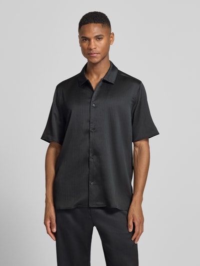 Męski model nosi Regular Fit Freizeithemd mit Kentkragen Modell 'Hector' od Les Deux, plisowana faktura, kolor czarny, krój regular fit, guziki, całkowity widok z przodu. Długość tyłu w rozmiarze M: 72 cm, szerokość ramion w rozmiarze M: 47 cm, długość rękawa w rozmiarze M: 27 cm.