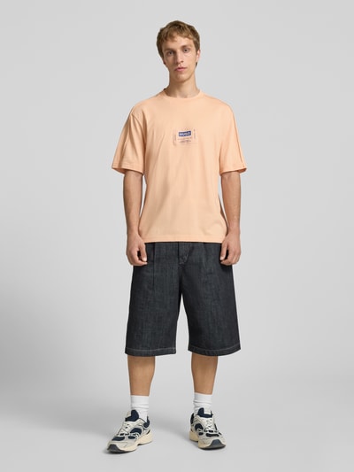 Männermodel trägt Regular Fit T-Shirt aus reiner Baumwolle Modell 'NURAZTI' von Hugo Blue in Uni-Optik mit Label Patch, Ganzkörperansicht von vorne.
