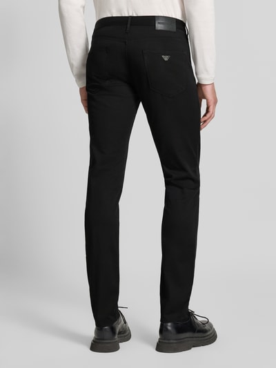 Männermodel trägt Skinny Fit Jeans aus Baumwoll-Mix von Emporio Armani in Schwarz, 5-Pocket-Design, Ganzkörperansicht Rückansicht.