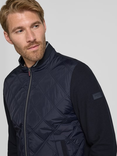 Männermodel trägt Regular Fit Collegejacke aus Baumwoll-Mix von Christian Berg Men, Stepp-Optik, dunkelblau, Nahaufnahme Oberkörper.