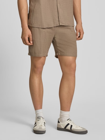 Männermodel trägt Regular Fit Shorts aus Viskose-Leinen-Mix Modell 'TEL LATHAM' von Only & Sons in Beige mit Strukturmuster, Nahaufnahme Oberschenkel.