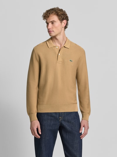 Męski model nosi Regular Fit Poloshirt aus reiner Baumwolle von Lacoste, beżowa koszulka polo, ciemnoniebieskie jeansy, Ganzkörperansicht z przodu, Herren Poloshirt von Lacoste.