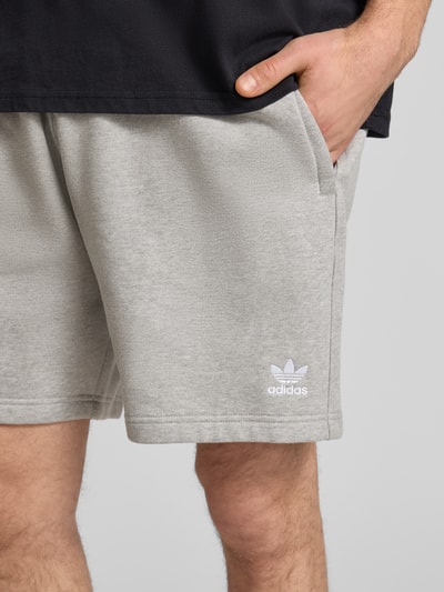 Männermodel trägt Regular Fit Sweatpants mit Logo-Stitching von adidas Originals in Hellgrau, Baumwoll-Mix, Nahaufnahme Oberschenkel.