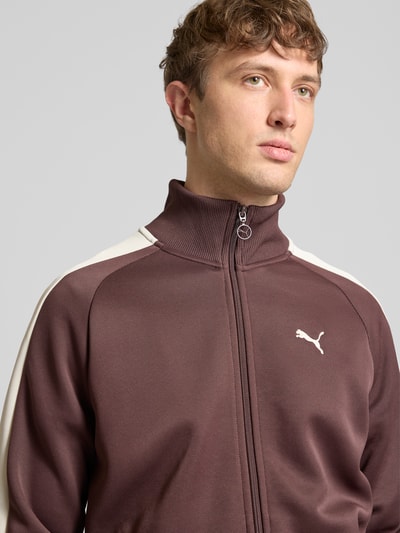 Männermodel trägt Sweatjacke mit Label-Print von PUMA PERFORMANCE in Braun mit weißen Details, Material-Mix, Nahaufnahme Oberkörper.